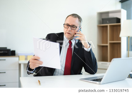 Professional businessman working at office with laptop, tablet, and notes. Perfect for business, finance, accounting, 133019745