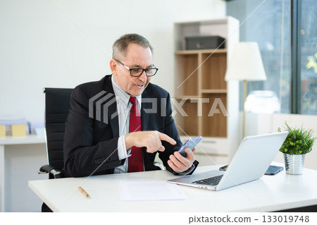 Mature business man executive manager looking at laptop watching online webinar training or having virtual working in office. 133019748