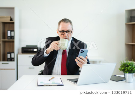 Mature business man executive manager looking at laptop watching online webinar training or having virtual working in office. Mature business man executive manager looking at laptop watching online webinar training or having virtual working in office. 133019751