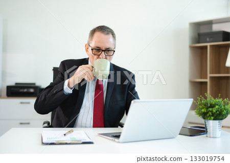 Mature business man executive manager looking at laptop watching online webinar training or having virtual working in office. 133019754