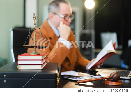 Male lawyer in the office with brass scale on wooden table. justice and law concept Male lawyer in the office with brass scale on wooden table. justice and law concept 133020106