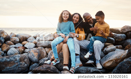 Adventure, beach and family relaxing on rocks while on summer vacation, travel or weekend trip. Sunset, portrait and parents bonding with their children by the ocean while on seaside tropical holiday 133020161