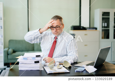 Angry and irritated Mature Businessman sitting in the office of laptop with his keyboard tired from work. Overwork, stress 133020189
