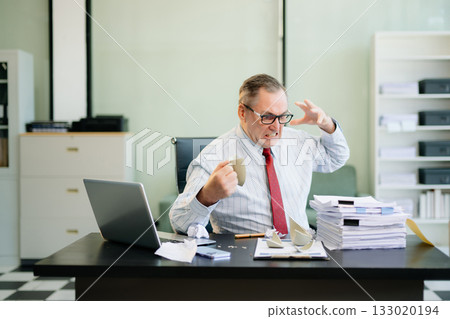 Angry and irritated Mature Businessman sitting in the office of laptop with his keyboard tired from work. Overwork, stress Angry and irritated Mature Businessman sitting in the office of laptop with his keyboard tired from work. Overwork, stress 133020194