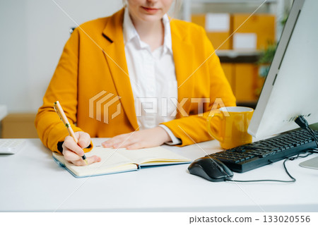 Young SME businesswoman in yellow blazer celebrates successful ecommerce delivery, smiling with parcel in hand at office desk. Online retail win. Real people. Young SME businesswoman in yellow blazer celebrates successful ecommerce delivery, smiling with parcel in hand at office desk. Online retail win. Real people. 133020556