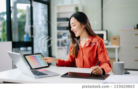 Asian graphic designer working on digital tablet with color swatches on screen. Concept of creativity, freelance design, digital content creation 133020603