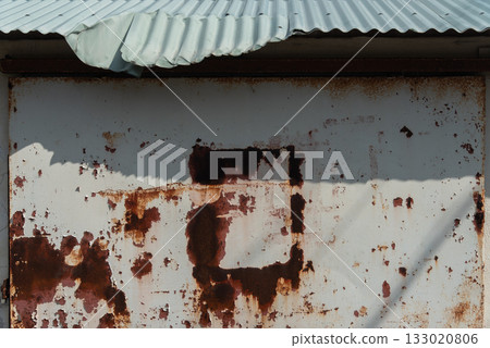 一棟老舊的建築,屋頂是彎曲的鐵皮,牆壁鏽跡斑斑。 一棟老舊的建築,屋頂是彎曲的鐵皮,牆壁鏽跡斑斑。 133020806