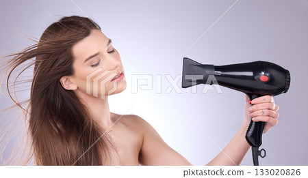Beauty, blowing and a woman drying her hair in studio on a gray background for grooming or style. Salon, cosmetics and appliance with an attractive young female indoor to blowdry while styling 133020826