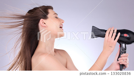 Beauty, straight hair and a woman blowing her hairstyle in studio on a gray background for grooming or style. Salon, cosmetics or salon with an attractive young female indoor to blowdry while styling 133020836