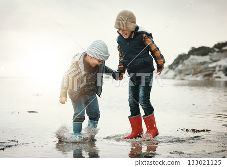 Beach, boots and children in water together, holding hands and playing in waves with smile. Fun, holiday and brothers, happy boys on ocean vacation at sunset, jumping and splash on evening sea walk. Beach, boots and children in water together, holding hands and playing in waves with smile. Fun, holiday and brothers, happy boys on ocean vacation at sunset, jumping and splash on evening sea walk. 133021125