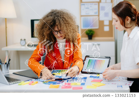UX UI designers working with color palettes, wireframes, and digital tablets in modern office. Creative teamwork, planning, branding and design strategy 133021153
