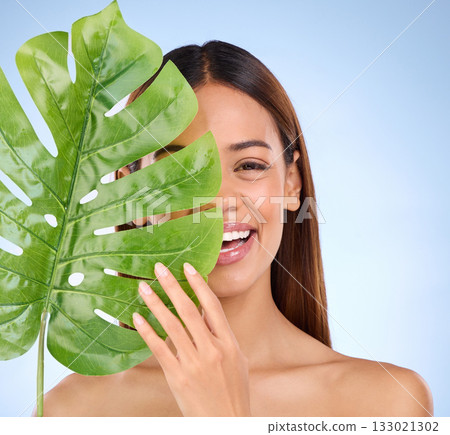 Happy woman, portrait and leaf in natural beauty and organic skincare cosmetics for self love or care on blue studio background. Female with smile holding eco green plant for sustainable wellness 133021302