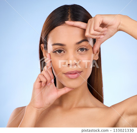Beauty, woman and hands on face portrait for skincare dermatology cosmetics in studio. Female model person on a blue background for self care, facial glow and healthy or clean skin with finger frame Beauty, woman and hands on face portrait for skincare dermatology cosmetics in studio. Female model person on a blue background for self care, facial glow and healthy or clean skin with finger frame 133021330