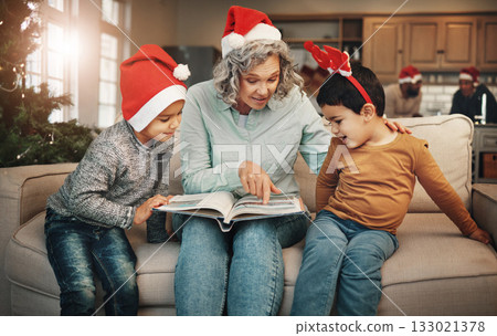 Christmas, photo album or children with a senior woman and kids looking at photographs during festive season. Family, love or celebration with a grandmother and grandchildren holding a picture book 133021378