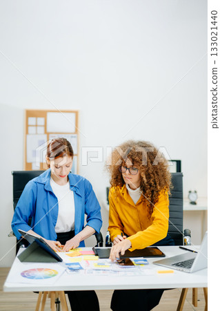 UX UI designers in modern office working on app wireframes, color palettes, and digital tools. Creative teamwork, planning, technology 133021440