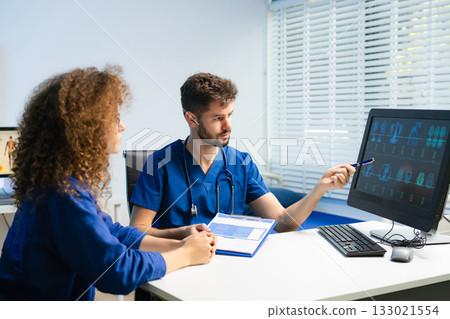 Male doctor explains health scan results to female patient using a computer screen. Concept of diagnosis, health tech, medical consultation 133021554