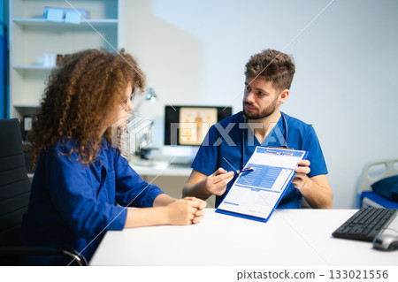 Doctor and young female patient reviewing medical form together. Concept of healthcare consultation Doctor and young female patient reviewing medical form together. Concept of healthcare consultation 133021556