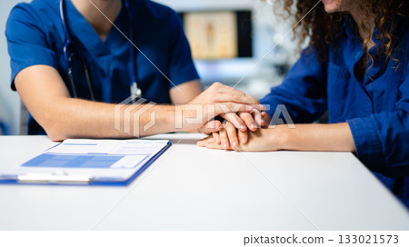 A compassionate doctor comforts a stressed female patient during a sensitive consultation. Concept of empathy, support A compassionate doctor comforts a stressed female patient during a sensitive consultation. Concept of empathy, support 133021573