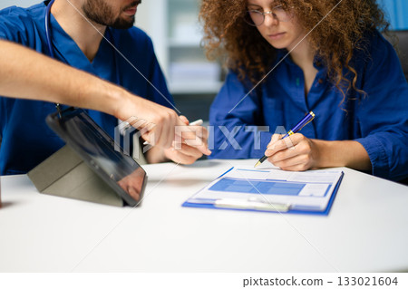 Doctor guides female patient to complete medical registration form. Concept of healthcare paperwork, consent, Doctor guides female patient to complete medical registration form. Concept of healthcare paperwork, consent, 133021604