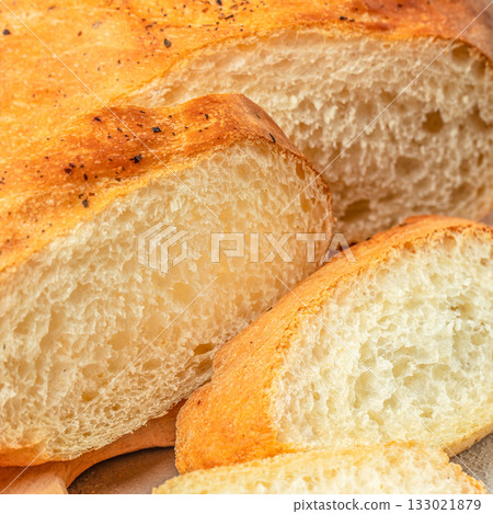 Freshly baked white bread loaf sliced on wooden board, close up 133021879