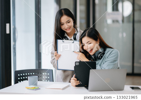 Two young Asian female college students working on the school project using laptop computer and tablet together Two young Asian female college students working on the school project using laptop computer and tablet together 133021965