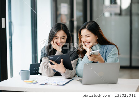 Two business workers talking on the smartphone and using laptop at modern office. 133022011