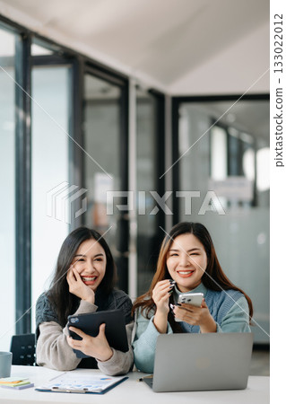 Two business workers talking on the smartphone and using laptop at modern office. 133022012