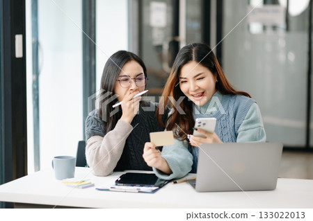 Two business workers talking on the smartphone and using laptop at modern office. 133022013