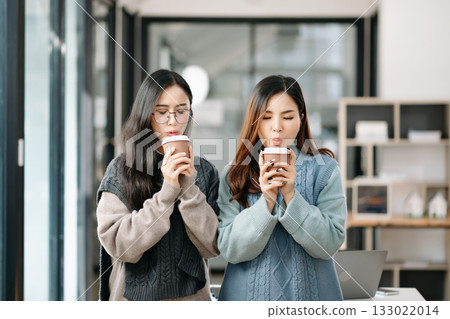 Two business workers talking on the smartphone and using laptop at modern office. 133022014
