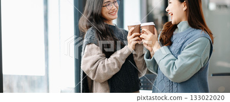 Happy two Asian business woman holding coffee cup in coworking office 133022020
