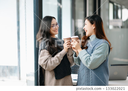 Two Attractive young Asian female college students working on the school project using laptop computer and tablet together, enjoy talking 133022021