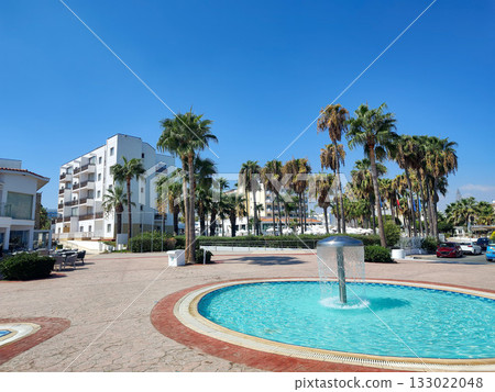 A Serene Coastal View Featuring Palm Trees and an Elegant Fountain by the Shoreline 133022048