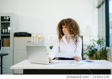 Successful businesswoman in office working on laptop.for doing math finance on an office desk, tax, report Successful businesswoman in office working on laptop.for doing math finance on an office desk, tax, report 133022136