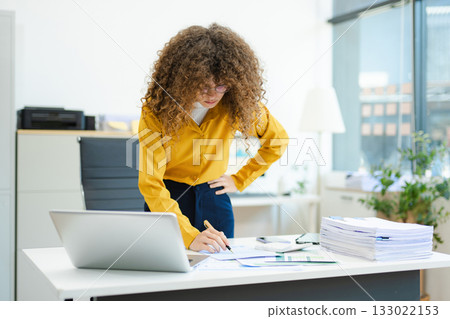 Confident businesswoman analyzing data on tablet at modern office desk with coffee, documents, and laptop. Concept of digital work Confident businesswoman analyzing data on tablet at modern office desk with coffee, documents, and laptop. Concept of digital work 133022153