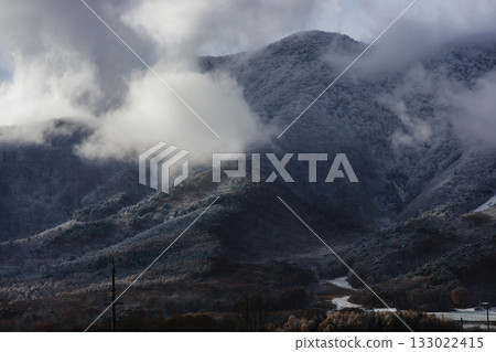 The mountainside covered in clouds and covered with the first snow 133022415