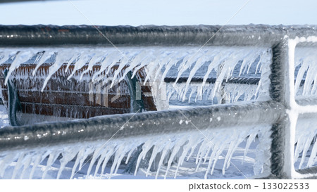 Beautiful Icicles Forming on a Metal Fence with Sunlight Creating a Sparkling Effect in Winter 133022533
