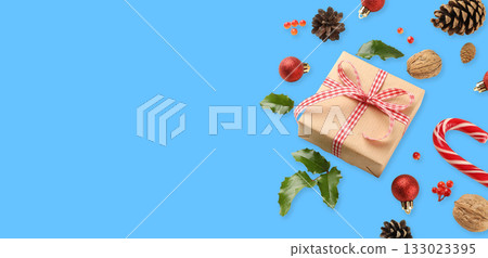 Gift box with ribbon, Christmas ornaments, and pinecones 133023395