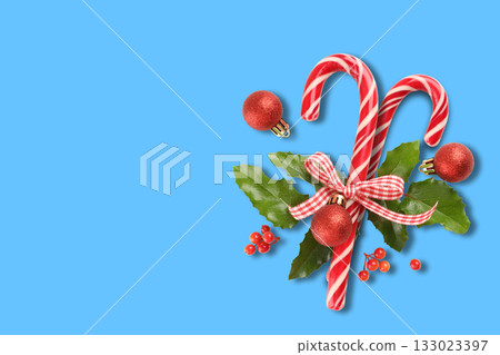 Candy canes are decorated with red ornaments and green leaves 133023397