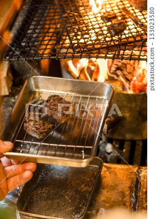 Meat dishes grilled over a wood fire - The immersive experience of a charcoal grill with rising flames Meat dishes grilled over a wood fire - The immersive experience of a charcoal grill with rising flames 133023580