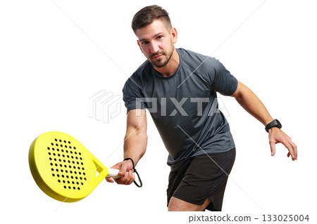Man playing paddle tennis with a bright yellow racket in casual sportswear Man playing paddle tennis with a bright yellow racket in casual sportswear 133025004