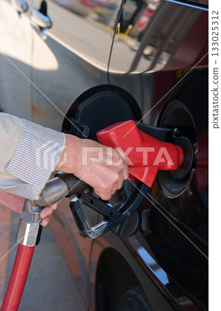 Hands of a woman refueling at a self-service gas station Hands of a woman refueling at a self-service gas station 133025312