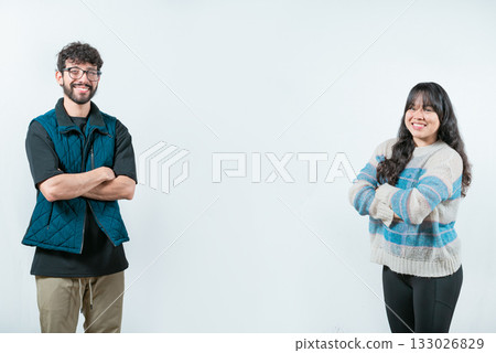 Cheerful young multiethnic couple with arms crossed, isolated. Smiling young couple with crossed arms looking at camera, isolated 133026829