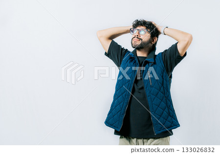 Relaxed young man in glasses with hands behind neck, isolated. Smiling calm guy with hands behind his neck 133026832