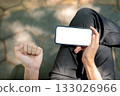 Top view a hand holding white screen smartphone horizontally and making a fist while sitting in park 133026966