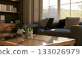 Coffee and potted plants on glass top wooden table with fabric sofas in living room or study room. 133026979