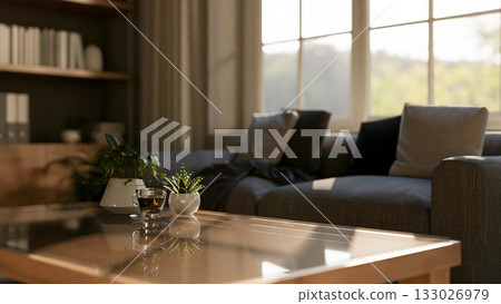 Coffee and potted plants on glass top wooden table with fabric sofas in living room or study room. Coffee and potted plants on glass top wooden table with fabric sofas in living room or study room. 133026979