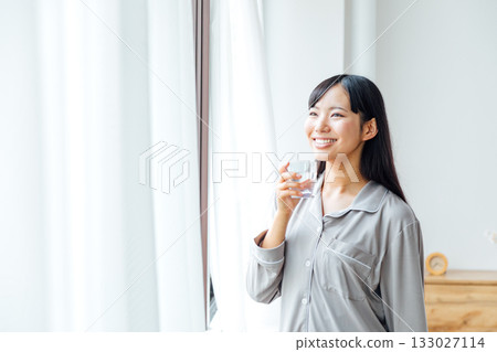 一位年輕女性注重健康的生活方式:早晨喝水的習慣 一位年輕女性注重健康的生活方式:早晨喝水的習慣 133027114