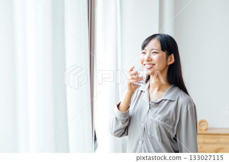 一位年輕女性注重健康的生活方式:早晨喝水的習慣 一位年輕女性注重健康的生活方式:早晨喝水的習慣 133027115