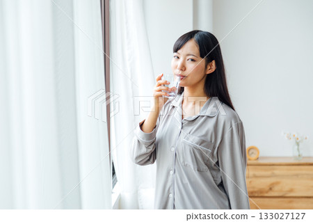 A young woman's well-being-conscious lifestyle: Morning routine of drinking water 133027127