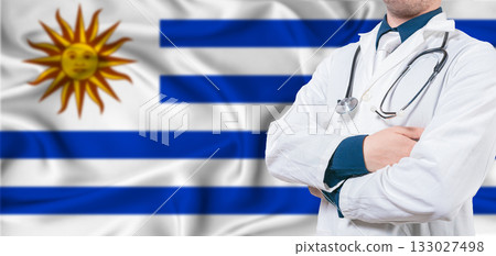 Uruguay healthcare concept. Male doctor on Uruguay flag. Doctor with crossed arms on Uruguay flag 133027498